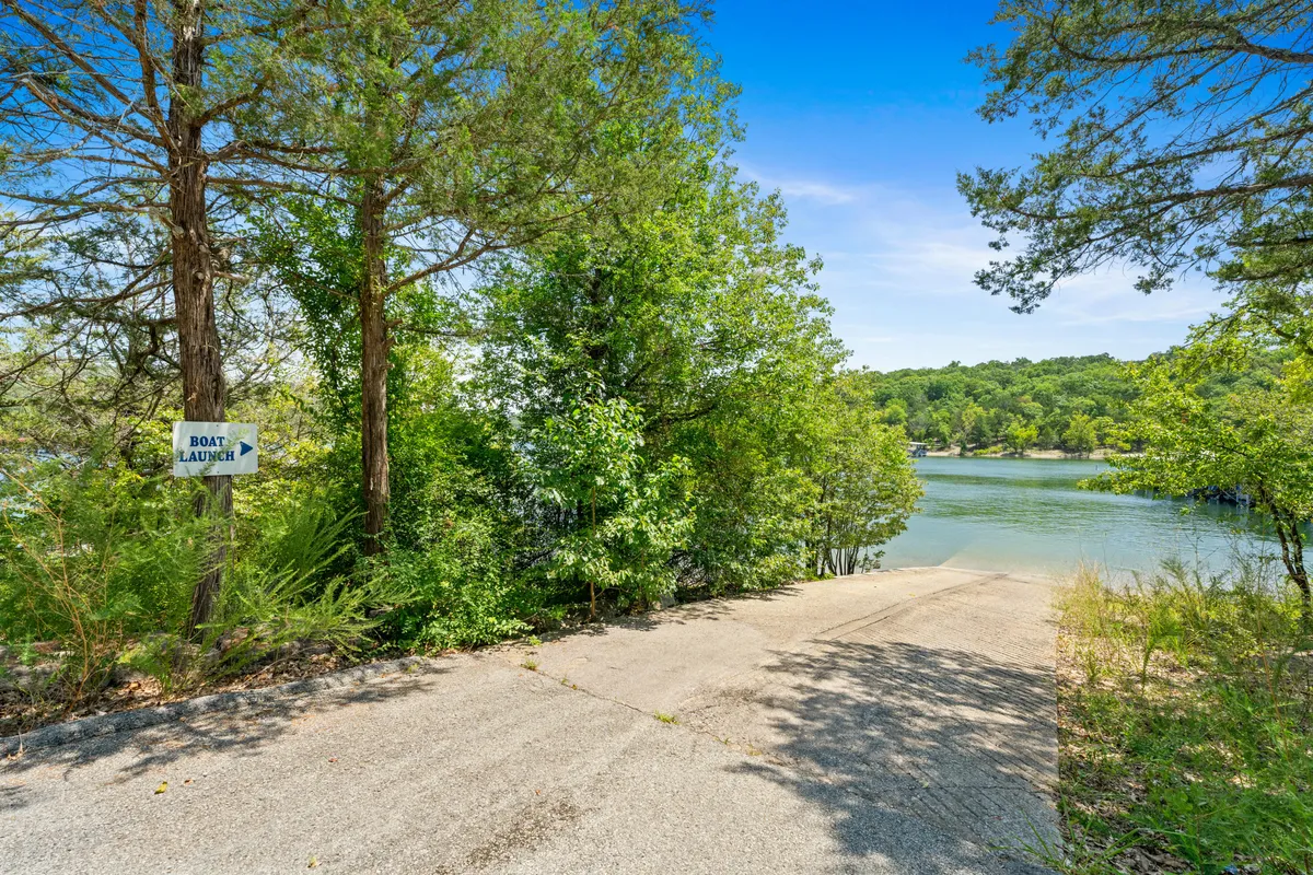 A clear view of a boat launch sign at the waterfront, with the shoreline and surrounding trees providing a natural, relaxed setting. The image captures the accessibility of the community boat ramp and the close proximity to water activities.