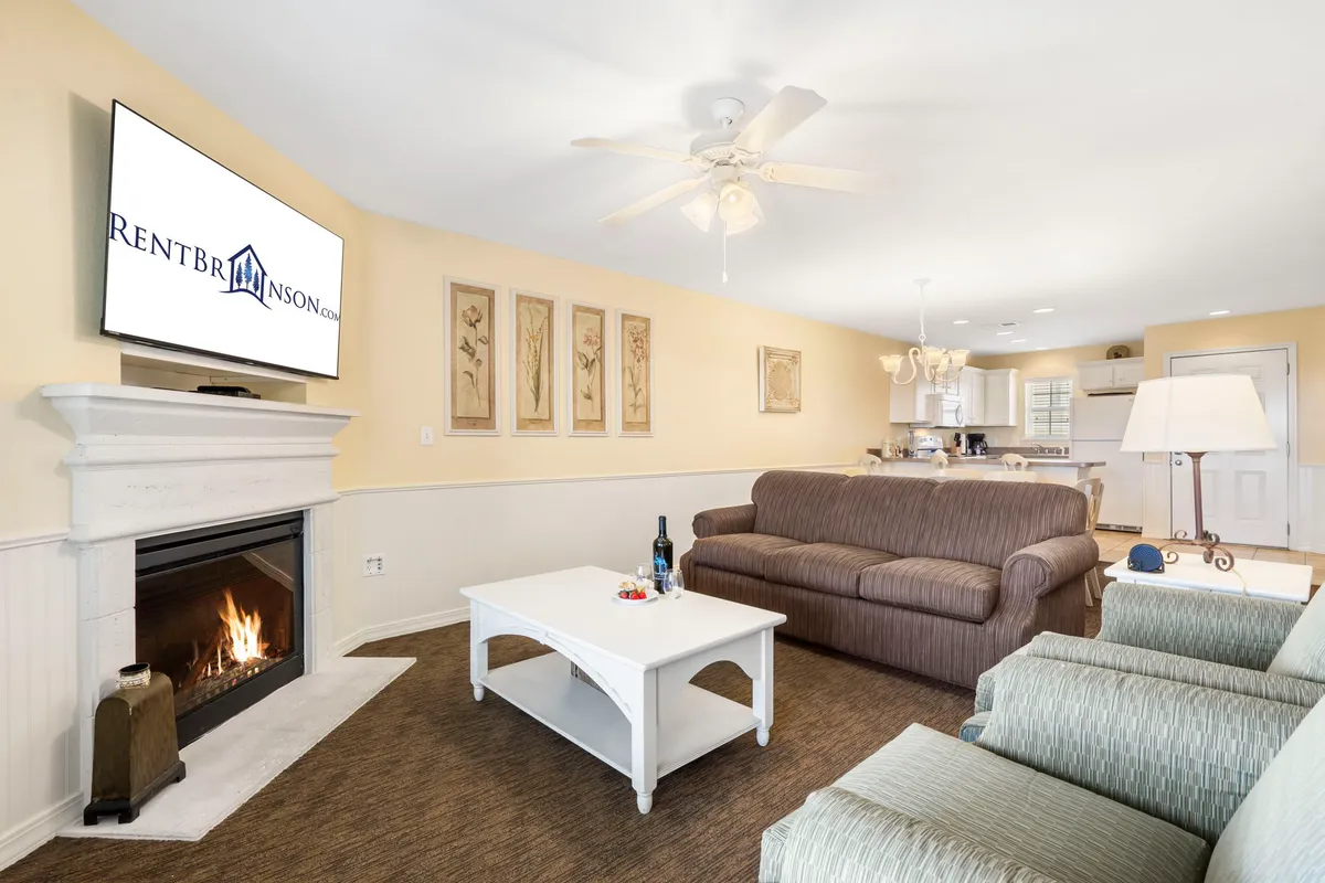 A cozy living room featuring a comfortable sofa, a coffee table, an electric fireplace, and a TV. The soft lighting and arrangement invite relaxation and socializing, with the fireplace serving as a focal point.