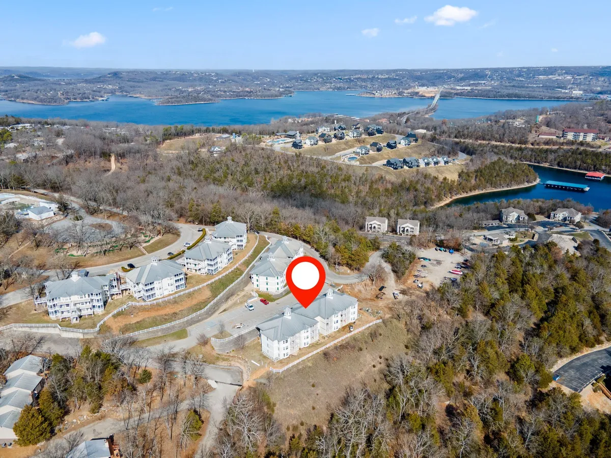 A scenic view of the lake with residential buildings nestled among trees and greenery. The tranquil setting features opportunities for boating, hiking, and outdoor gatherings, capturing the peaceful natural beauty surrounding the resort.