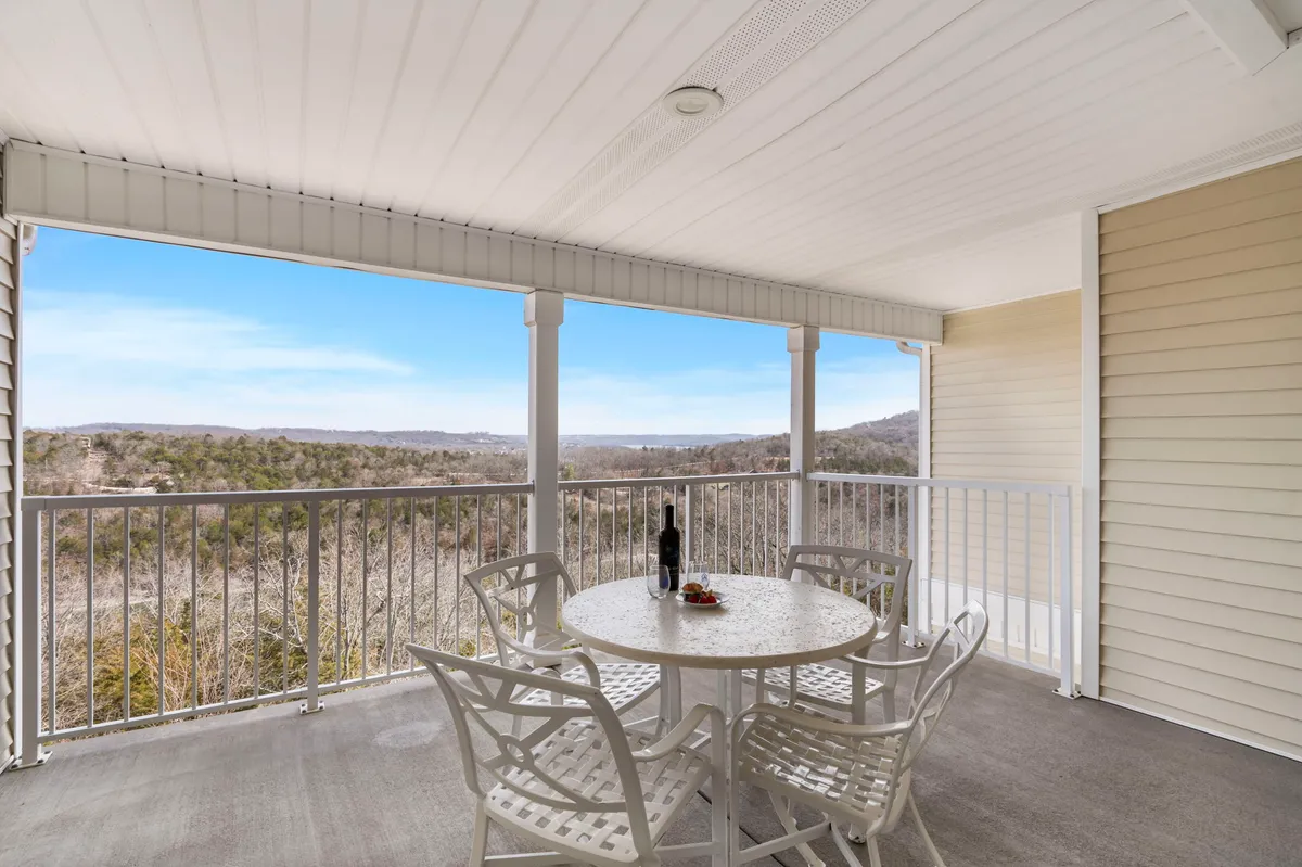 A private deck with a table set for wine and snacks, a railing, and a scenic landscape view, capturing the tranquil outdoor experience just steps from the main living space.