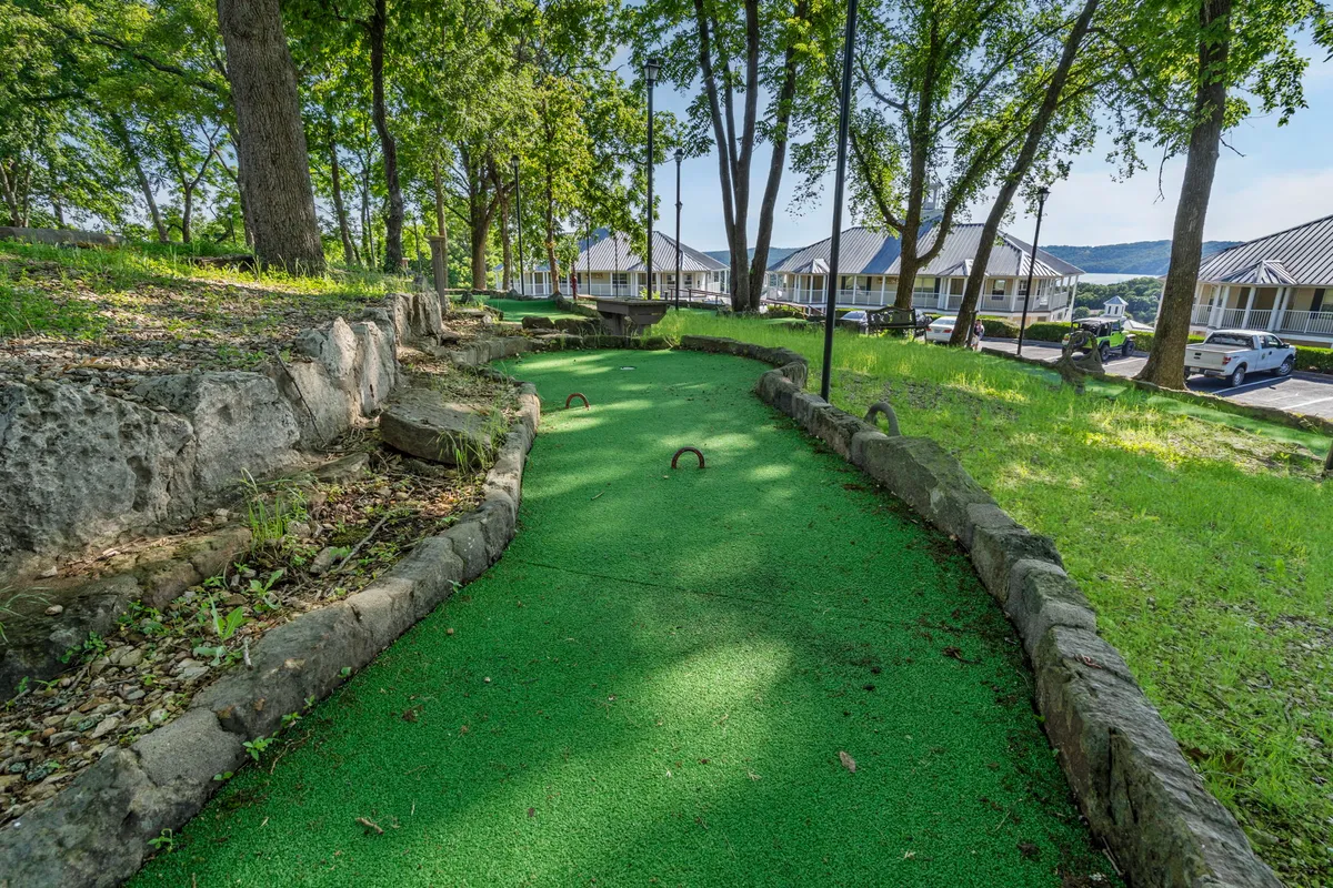 This image displays a vibrant mini-golf course nestled among lush greenery with a stone pathway winding through the area. The scene exudes a sense of joyful activity, perfect for families or friends aiming for playful competitions and lasting vacation memories.